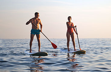 Skupina ljudi se ukvarja s stoječim veslanjem (SUP) na Jadranskem morju