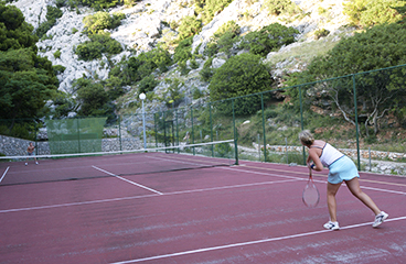 Mensen die tennis spelen op de tennisbaan in Naturist Camp Bunculuka