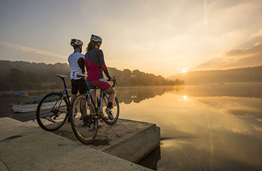Ein Paar beobachtet den Sonnenuntergang, während es auf Fahrrädern auf einem Pier am Adriatischen Meer steht