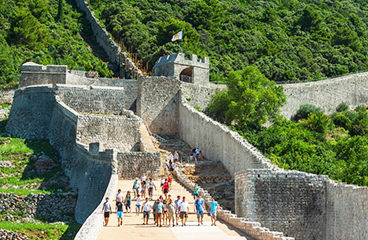 Gruppe von Menschen, die in Ston spazieren gehen, einer Stadt aus dem 15. Jahrhundert mit Stadtmauern, die fünf Kilometer lang sind