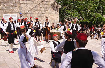 Ljudje v tradicionalnih hrvaških kostumih plešejo v mestu Čilipi, blizu Konavle