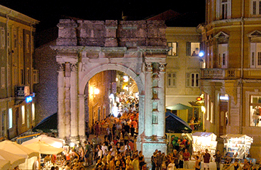 Folle che passano attraverso l'Arco dei Sergii, un antico arco di trionfo romano situato a Pola