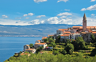 Piccola città di Vrbnik in cima a una collina verde