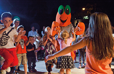 Otroci plešejo z maskoto Maro v diskoteki Maro