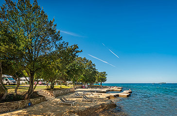 Spiaggia rocciosa Marina all'ombra degli alberi con aree per prendere il sole