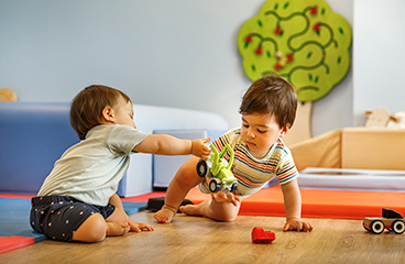 Zwei Babyjungen spielen im Maro Baby Room für Babys und Kleinkinder unter Aufsicht von geschultem Personal