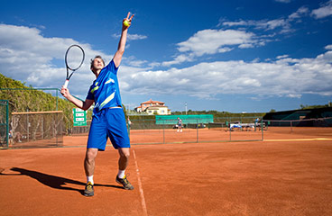 Muškarac igra tenis na teniskom terenu