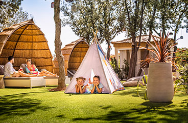 Two kids lying in a tent at the Spa Zone with adults lounging in beds in the background