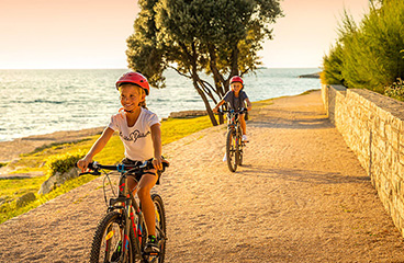 Due ragazzi vanno in bicicletta lungo il mare