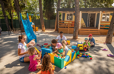 Dva otroka igrata igro pod strokovnim nadzorom v otroški igralnici, kjer so organizirane različne aktivnosti.