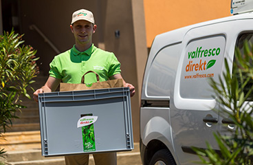 Een man houdt een doos vol met vers voedsel en heerlijke kant-en-klare maaltijden die u kunt bestellen in onze Valfresco Direkt Shop