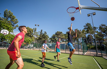 Jugendliche spielen Basketball auf einem Mehrzwecksportplatz für Basketball und Kleinfeldfußball