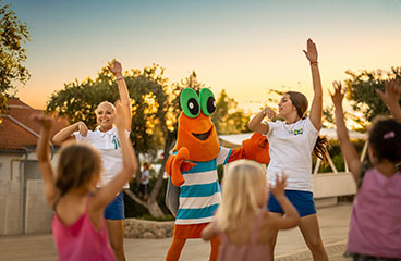 Personale addestrato e la mascotte Maro ballano durante un programma di intrattenimento e performance
