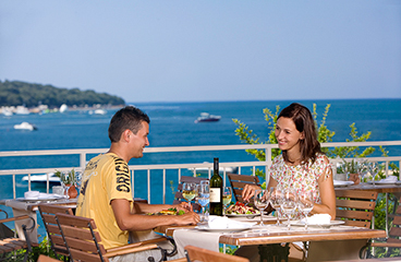 Paar isst im Oliva Grill, der einen Panoramablick auf das Meer und köstliche gegrillte Spezialitäten bietet