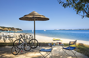 a bicycle parked next to a table and chairs on a beach