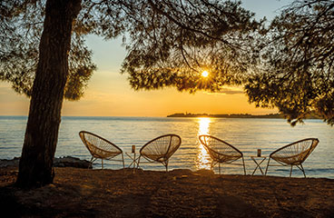 Twee tafels van het Tuna Bay restaurant direct aan het strand bij zonsondergang