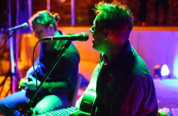 a man playing a guitar next to a man playing a keyboard