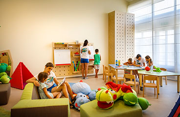 Usposobljeno osebje se uči z otroki v mehkem igralnem prostoru - sodobna igralnica z različnimi zabavnimi elementi