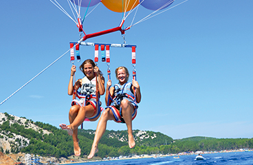 Zwei Mädchen halten ihre Fallschirme fest, während sie von einem Boot gezogen werden