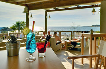 Bunte Cocktails im Restaurant, Cocktail & Lounge Bar Pharos mit dem Meer im Hintergrund