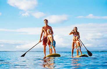 Una famiglia di quattro persone fa paddleboarding in piedi su due SUP