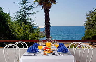 Tisch mit Essen und Getränken auf der Terrasse des Buffets Kopalo mit Meerblick