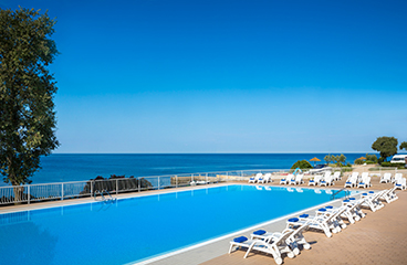 Außenpool mit Liegestühlen und Sonnenschirmen mit Blick auf das Adriatische Meer