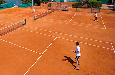 Menschen spielen Tennis auf zwei nebeneinander liegenden Tennisplätzen