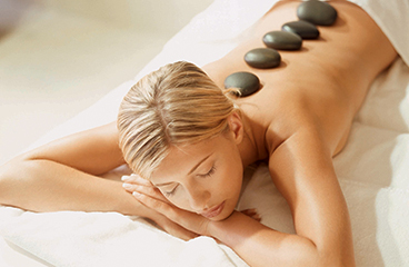 Ženska uživa v sproščujoči masaži s kamni v wellness centru