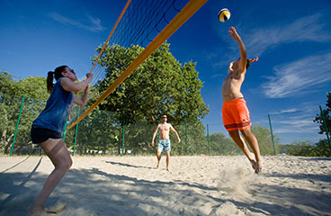 a group of people playing volleyball on a beach